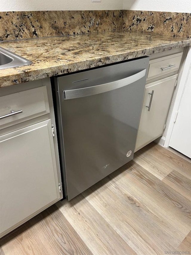 details with light hardwood / wood-style flooring, stone counters, stainless steel dishwasher, and white cabinets