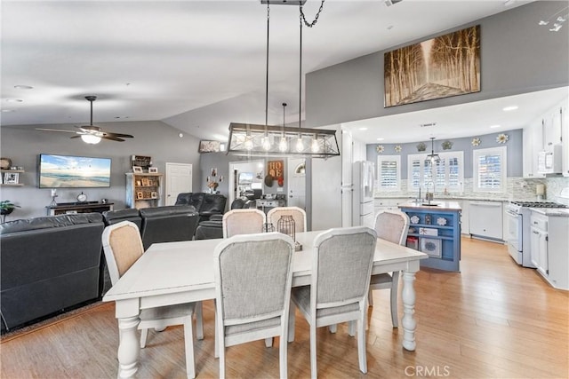 dining room featuring light wood-type flooring, ceiling fan, and vaulted ceiling