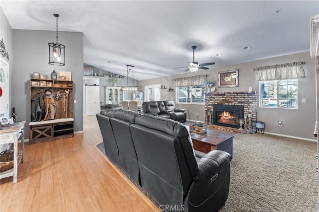 living room with a brick fireplace, lofted ceiling, hardwood / wood-style flooring, and ceiling fan