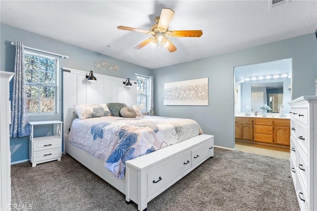 carpeted bedroom featuring ensuite bathroom, ceiling fan, and multiple windows