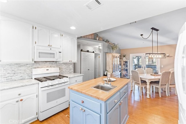 kitchen with white cabinetry, sink, white appliances, and a barn door