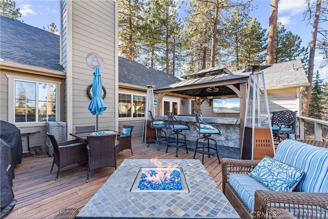 deck featuring an outdoor living space with a fire pit, a gazebo, and a bar