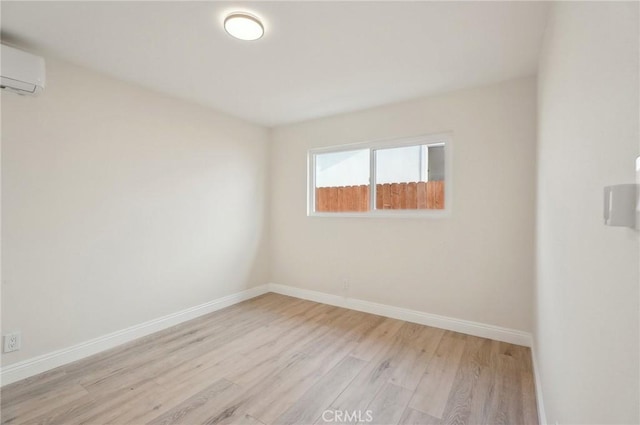 unfurnished room featuring light hardwood / wood-style floors and a wall unit AC