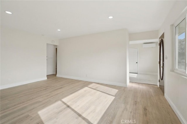 unfurnished room with light wood-type flooring and a wall mounted air conditioner