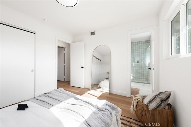 bedroom with a closet, connected bathroom, and light hardwood / wood-style floors