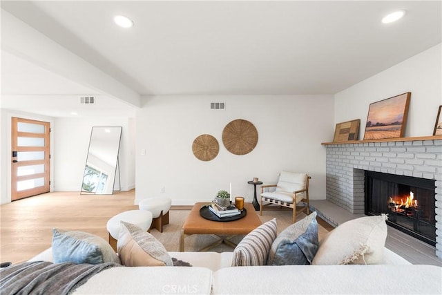 living room with a brick fireplace and light hardwood / wood-style floors