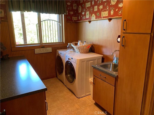 clothes washing area featuring washer and clothes dryer, sink, and cabinets