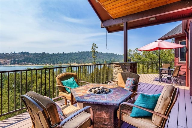 wooden terrace with an outdoor fire pit and a water view