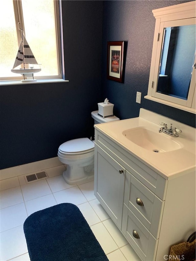 bathroom with toilet, vanity, and tile patterned flooring