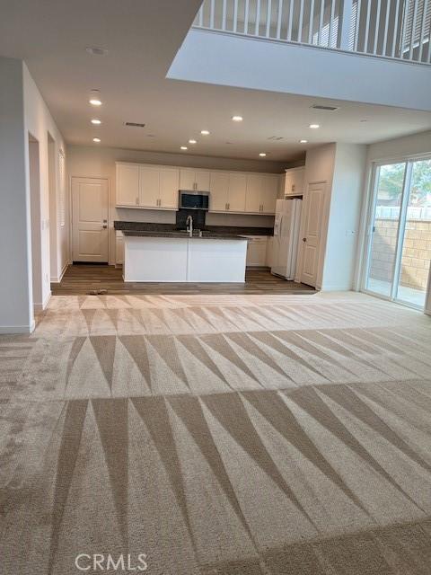 unfurnished living room with light colored carpet and sink