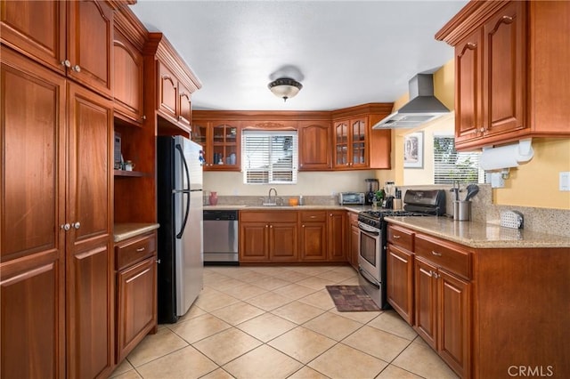 kitchen featuring wall chimney range hood, sink, stainless steel appliances, light tile patterned floors, and light stone counters