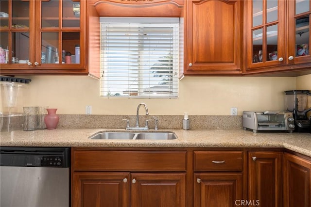 kitchen with stainless steel dishwasher, light stone countertops, and sink