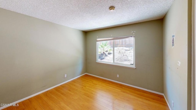 spare room with a textured ceiling and wood-type flooring