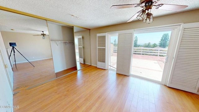 unfurnished bedroom featuring access to outside, ceiling fan, light wood-type flooring, and a textured ceiling