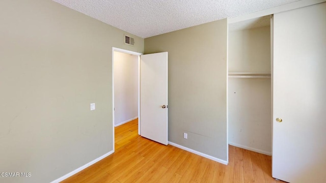 unfurnished bedroom with a textured ceiling, a closet, and light hardwood / wood-style flooring