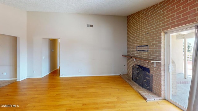 unfurnished living room featuring a fireplace, a textured ceiling, and light hardwood / wood-style floors