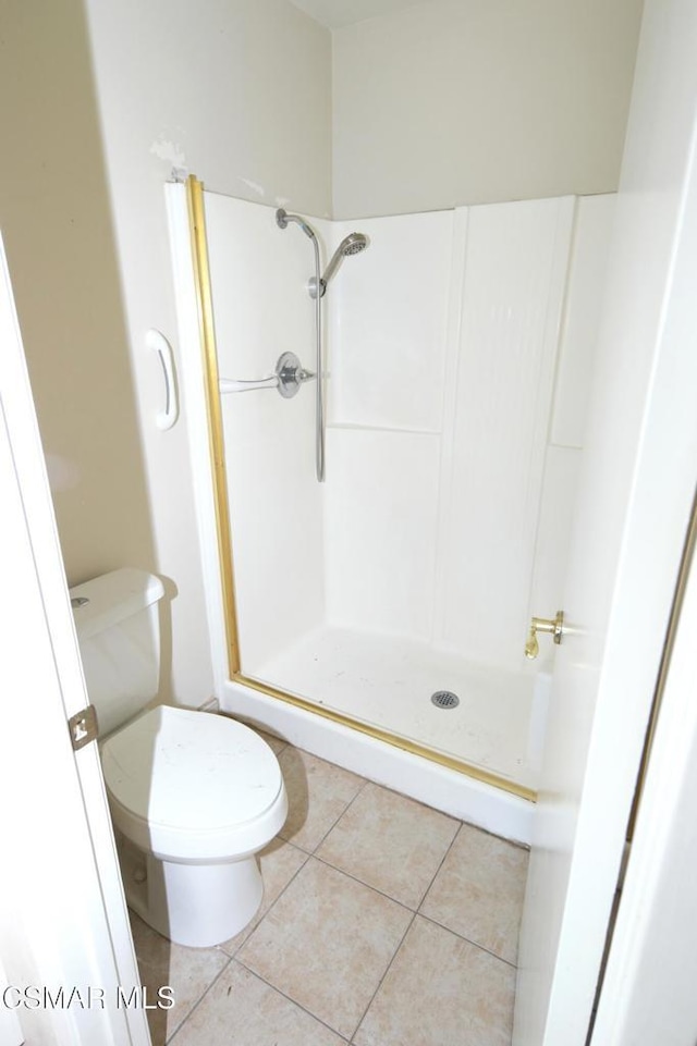 bathroom with toilet, tile patterned flooring, and a shower