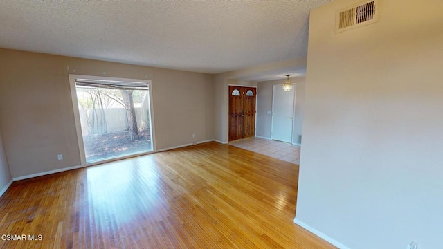 spare room featuring a textured ceiling and light hardwood / wood-style flooring