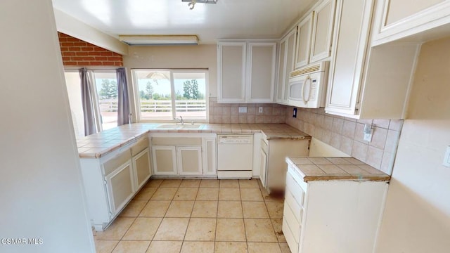 kitchen featuring backsplash, tile countertops, sink, white appliances, and white cabinetry