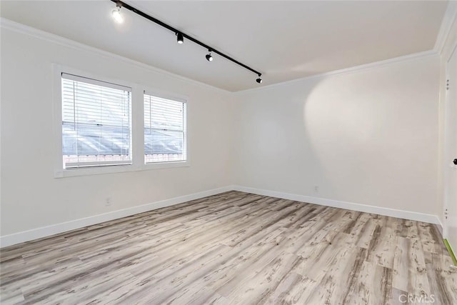 empty room with rail lighting, ornamental molding, and light wood-type flooring