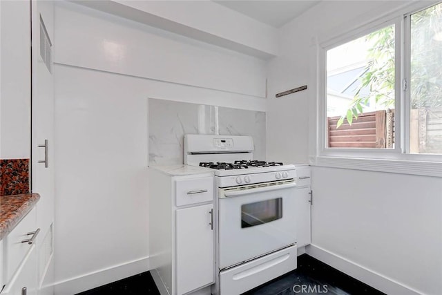 kitchen with white gas stove and white cabinetry