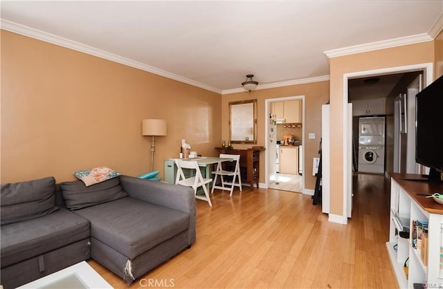 living room featuring stacked washer and dryer, ceiling fan, ornamental molding, and light hardwood / wood-style flooring