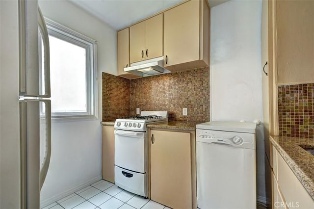 kitchen with tasteful backsplash, white appliances, light tile patterned floors, dark stone counters, and cream cabinets