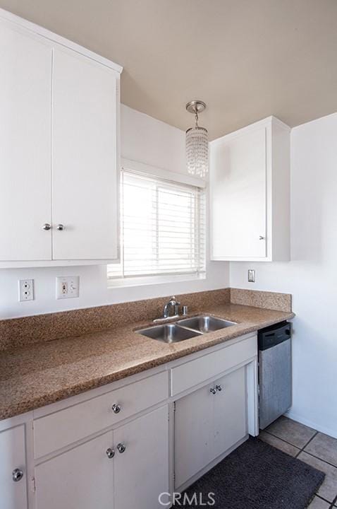 kitchen featuring stainless steel dishwasher, sink, hanging light fixtures, and white cabinetry