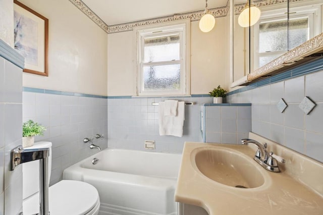 bathroom featuring sink, a bathtub, tile walls, and toilet