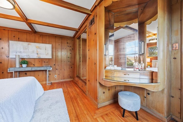 bedroom featuring beam ceiling, wooden walls, coffered ceiling, and light wood-type flooring