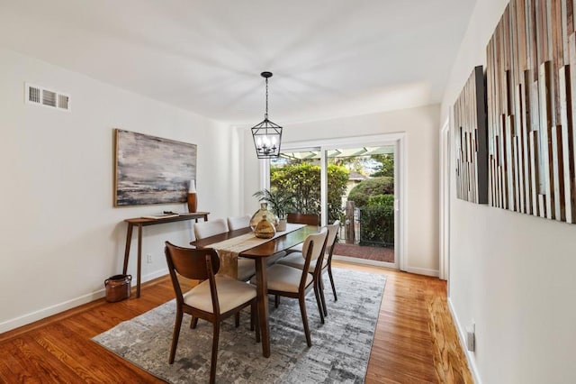 dining space with wood-type flooring and an inviting chandelier