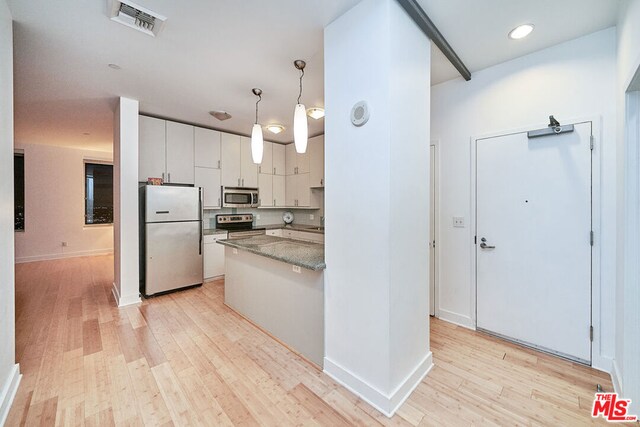 kitchen with white cabinets, hanging light fixtures, appliances with stainless steel finishes, and light wood-type flooring