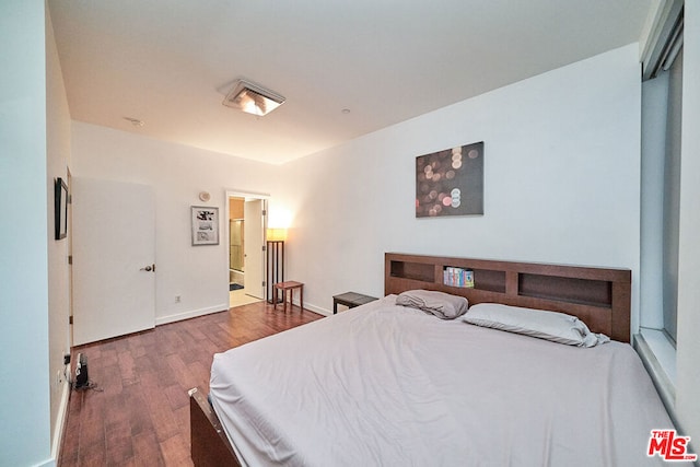 bedroom featuring dark hardwood / wood-style flooring and connected bathroom