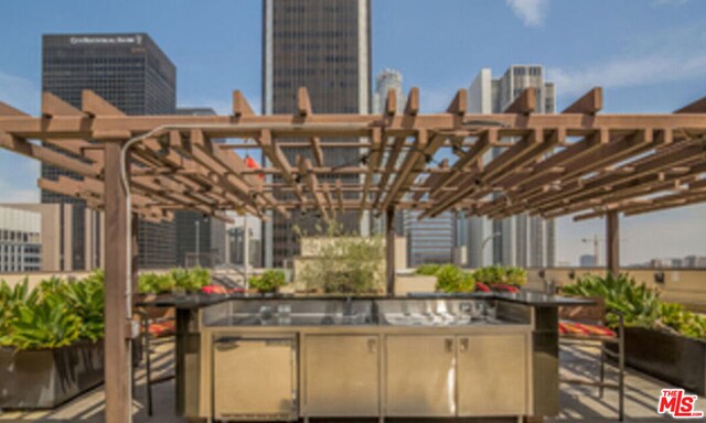 view of patio / terrace with central AC, an outdoor kitchen, and a pergola