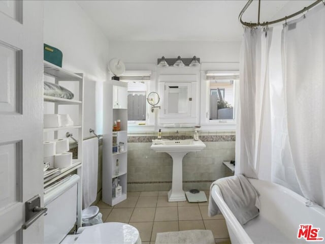 bathroom with tile walls, tile patterned floors, shower / bath combo with shower curtain, and toilet