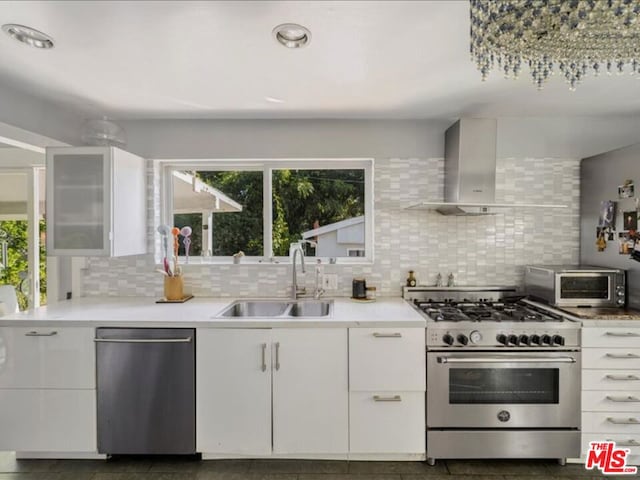 kitchen with white cabinetry, stainless steel appliances, sink, and wall chimney range hood