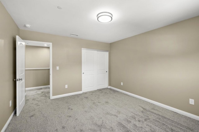 unfurnished bedroom with a closet and light colored carpet