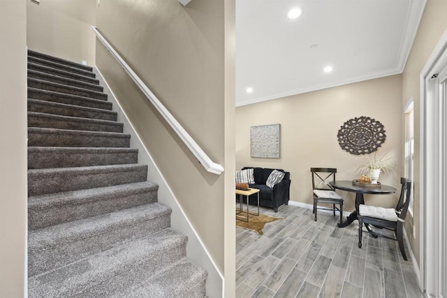 staircase with ornamental molding and hardwood / wood-style floors