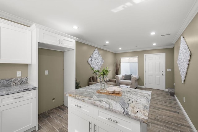 kitchen featuring white cabinetry, crown molding, a center island, and light stone countertops