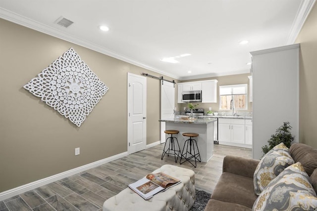 living room with crown molding, a barn door, and sink