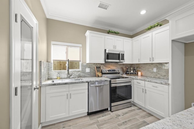 kitchen with light stone countertops, sink, white cabinetry, and stainless steel appliances