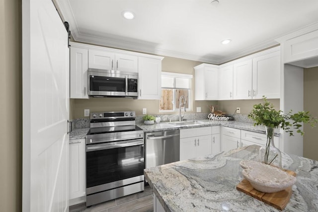 kitchen featuring white cabinets, appliances with stainless steel finishes, and a barn door