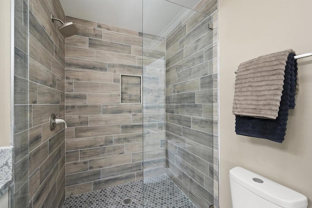 bathroom featuring toilet and a tile shower