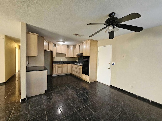 kitchen featuring a textured ceiling, double oven, sink, ceiling fan, and gas stovetop