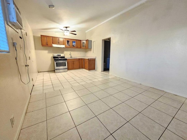 kitchen featuring stainless steel range oven, sink, ceiling fan, light tile patterned floors, and a wall mounted air conditioner