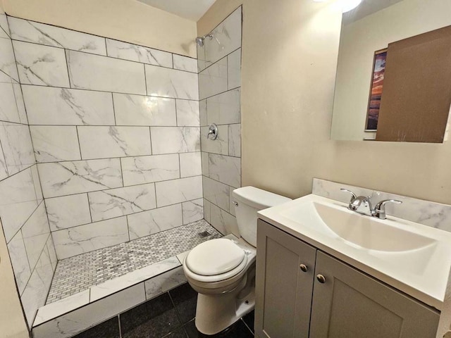 bathroom featuring toilet, tile patterned flooring, a tile shower, and vanity