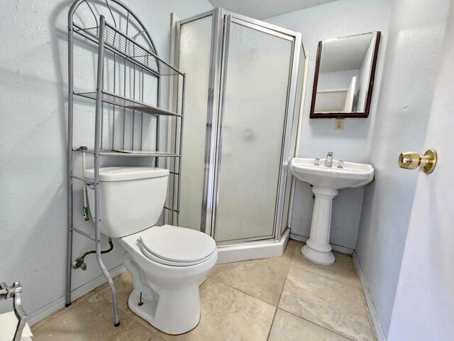 bathroom with toilet, sink, tile patterned floors, and a shower with door