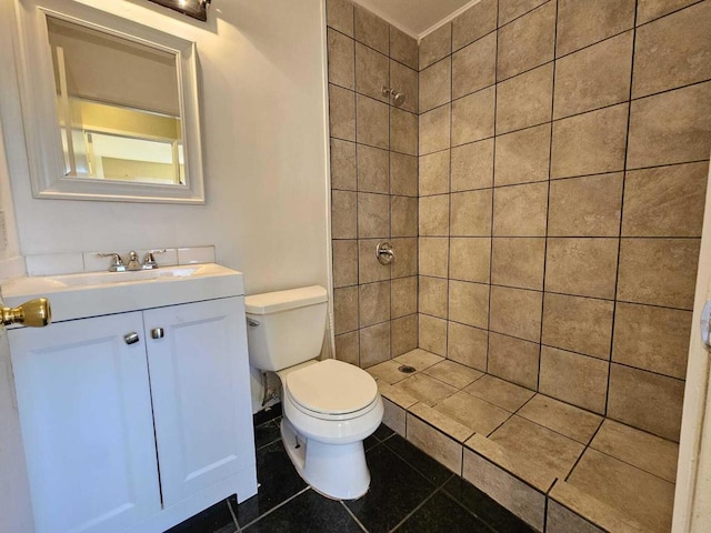 bathroom with tile patterned floors, tiled shower, vanity, and toilet