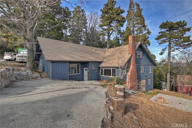 rustic home featuring a shingled roof and a chimney