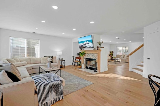 living room with light hardwood / wood-style flooring and a stone fireplace